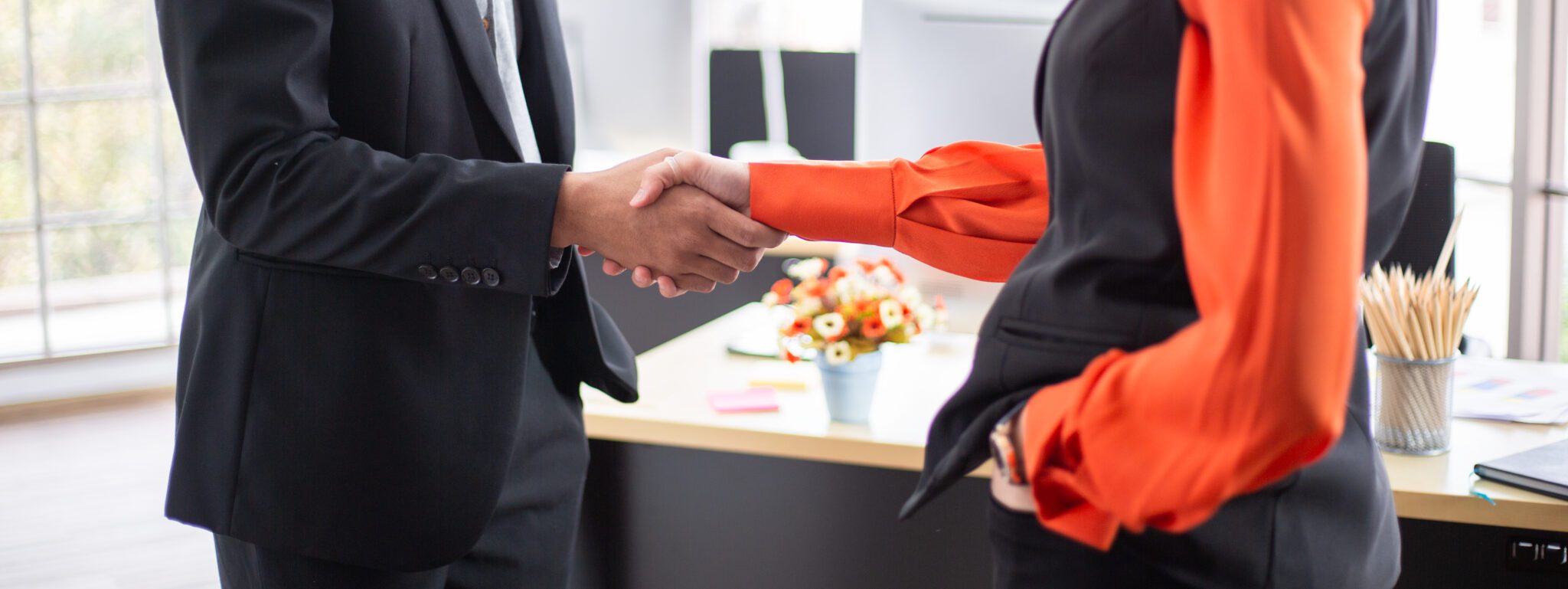 wo professionals shaking hands in a business setting, symbolizing partnership and collaboration