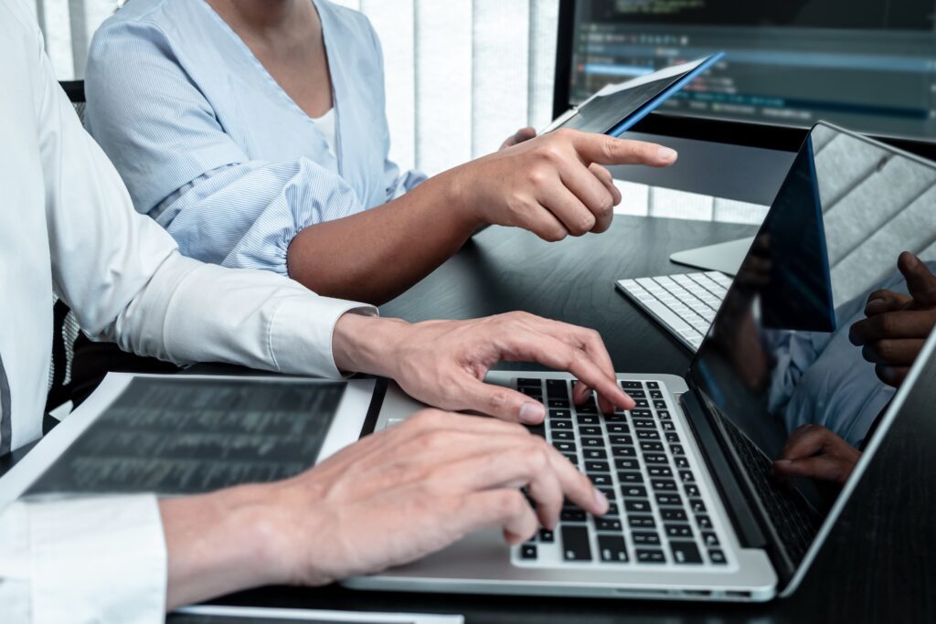 Close-up of two professionals collaborating on a computer, analyzing fintech data and digital solutions.